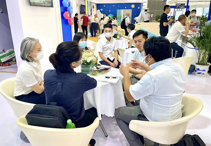 Professional technical consultation for hygiene raw material supply chain solutions at an international trade show booth.